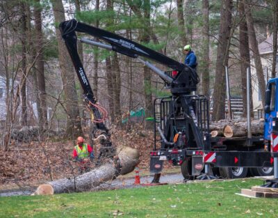 The American Climbers removal crew uses a grapple arm on a knuckle boom to lift a large section of tree. Massachusetts law has determined that the property owner is probably responsible for a fallen tree in this case.
