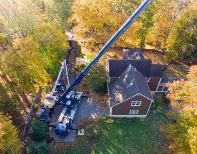 Aerial view of American Climbers crane with outrigger pads protecting residential property during tree removal in MetroWest neighborhood.