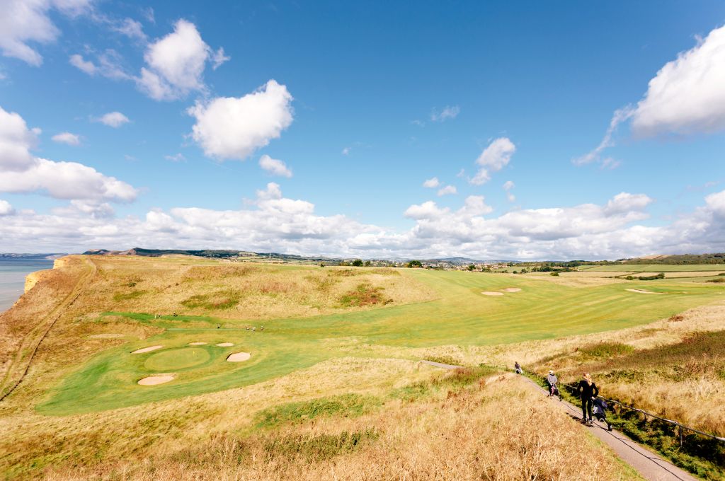 A golf course in the United Kingdom designed as a links golf course, near the ocean with few or no trees.