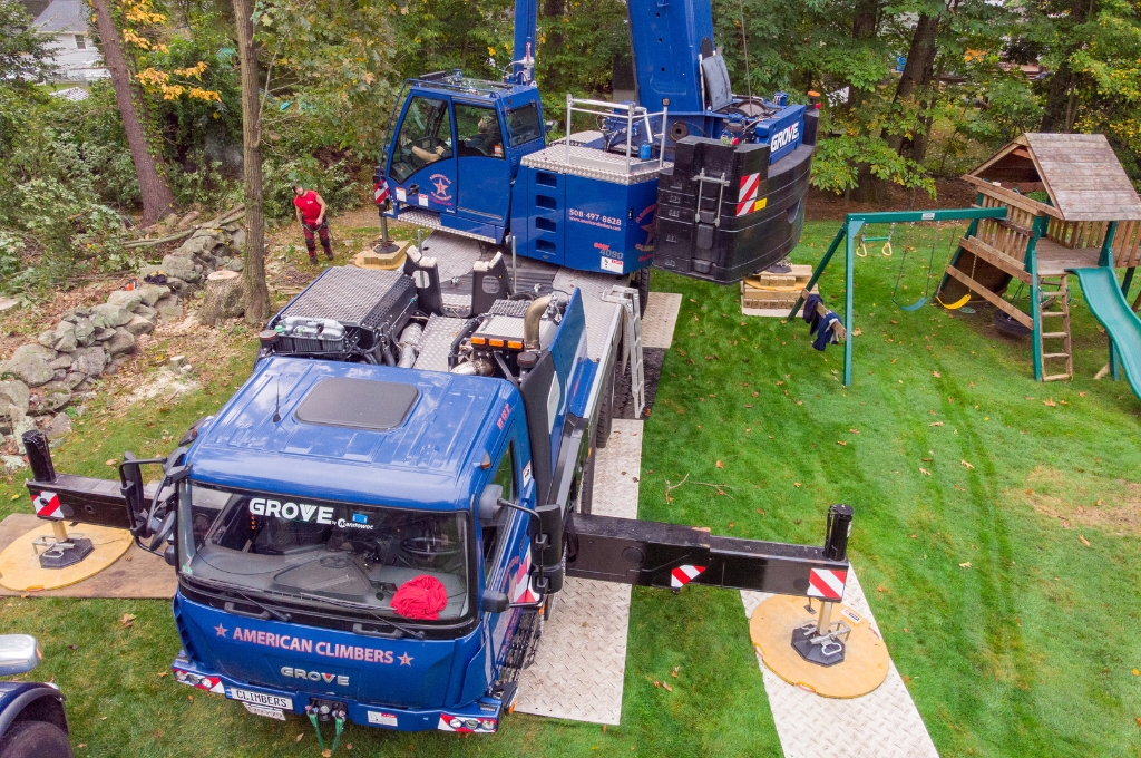Will a Crane Damage My Property? MetroWest Homeowner's Guide to Crane-Assisted Tree Removal American climbers grove crane with white outrigger pads protecting residential lawn during professional tree service in metrowest.