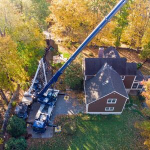 Aerial view of American Climbers crane with outrigger pads protecting residential property during tree removal in MetroWest neighborhood.
